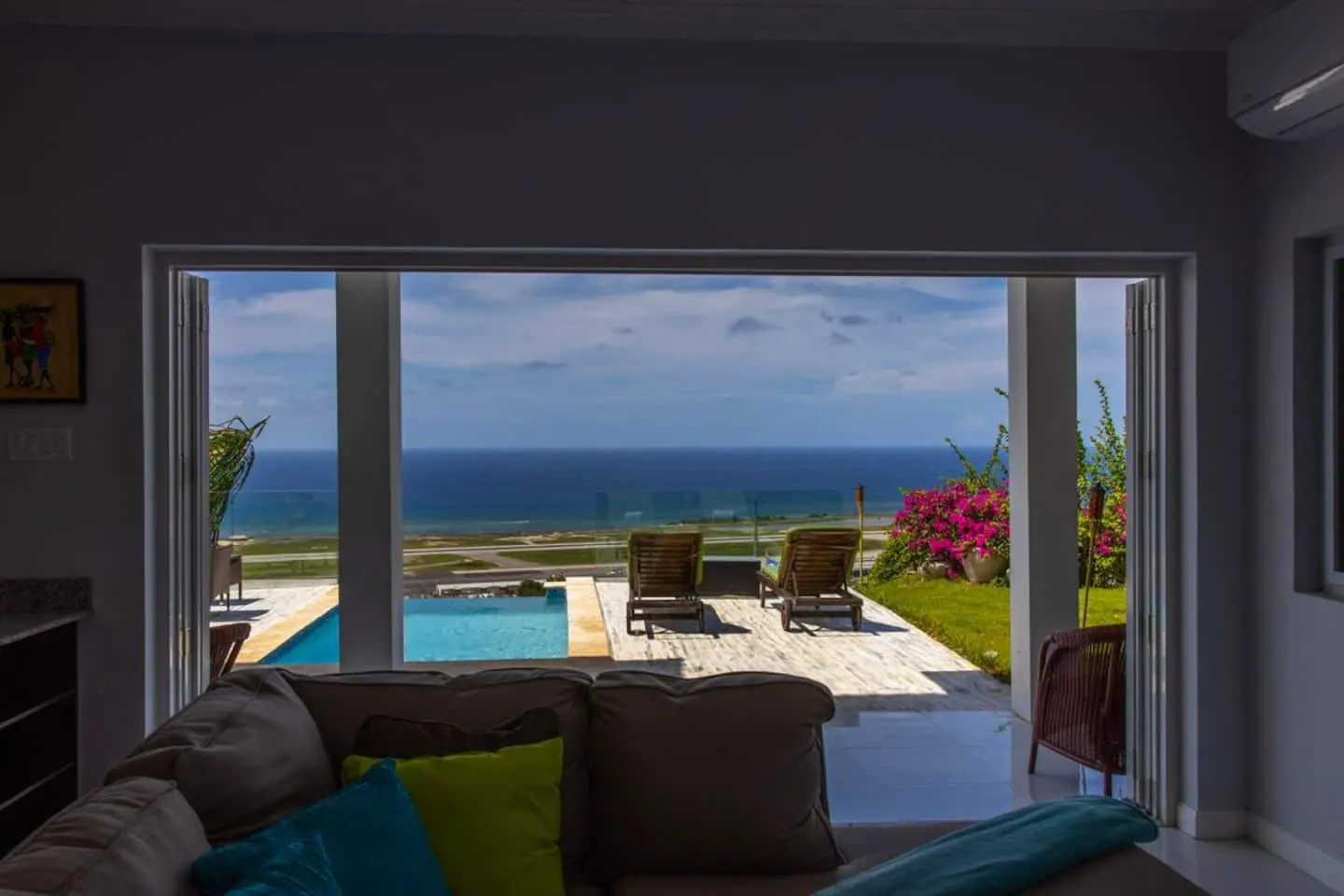 Living room doors open toward the pool terrace and sea view.