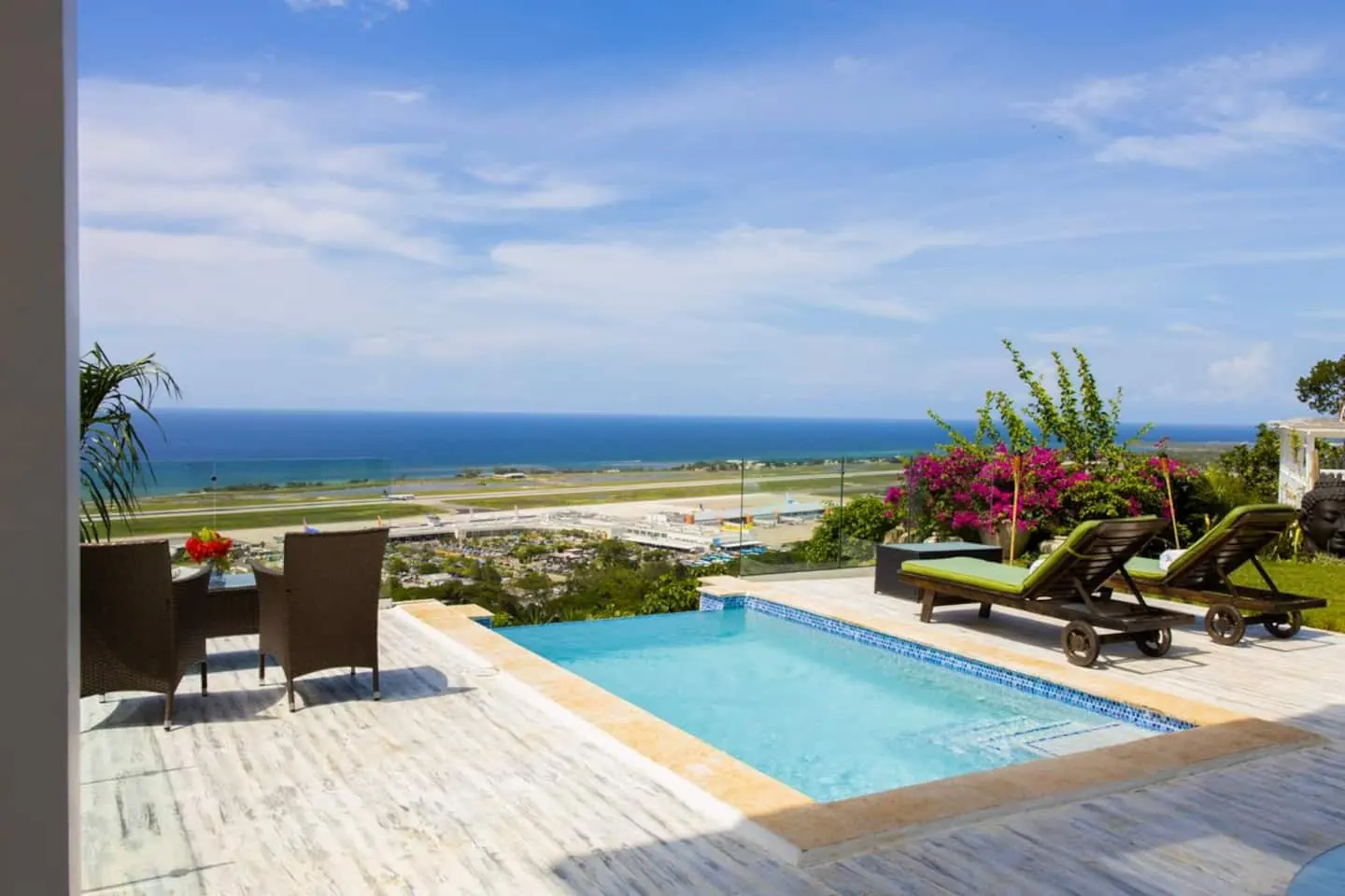 Pool terrace with loungers and outdoor seating, facing the airport and sea.